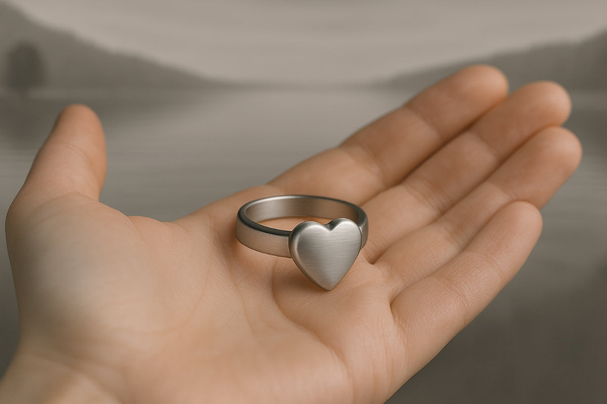 Bague cœur commémorative posée dans une main dans un univers sobre et apaisant