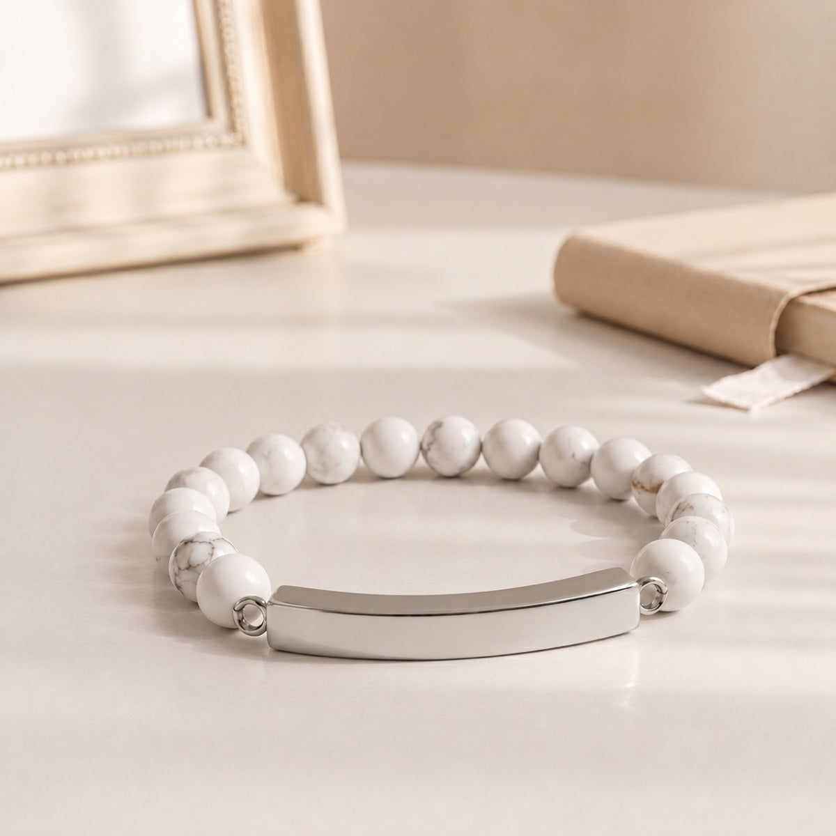 Bracelet pierre du souvenir blanc metal-gris avec perles effet marbre blanc et barre présenté dans une ambiance intérieure raffinée