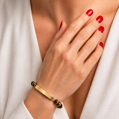 Bracelet pierre du souvenir marron metal-jaune avec barre porté au poignet dans un style élégant et discret