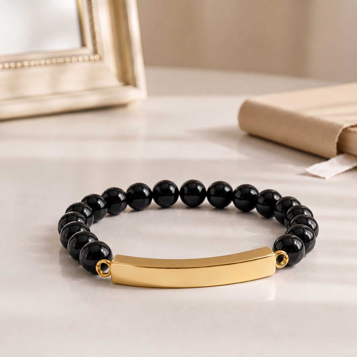 Bracelet pierre du souvenir noir metal-jaune avec perles noires et barre présenté dans une ambiance intérieure raffinée