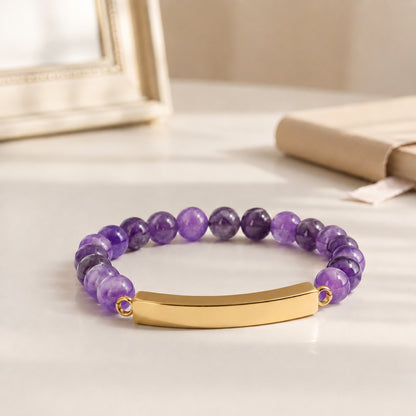 Bracelet pierre du souvenir violet metal-jaune avec perles effet pierre violette et barre présenté dans une ambiance intérieure raffinée
