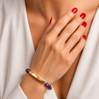 Bracelet pierre du souvenir violet metal-jaune avec barre porté au poignet dans un style élégant et discret
