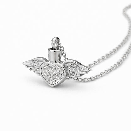 Vue 3/4 du collier cœur ailé urne en acier inoxydable argenté mettant en valeur ses ailes et son compartiment intégré