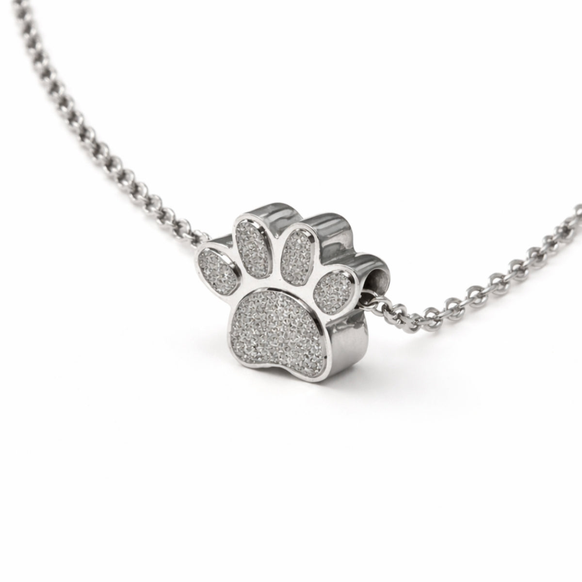 Vue 3/4 du collier empreinte fidèle urne en acier inoxydable argenté mettant en valeur son relief et son compartiment intégré