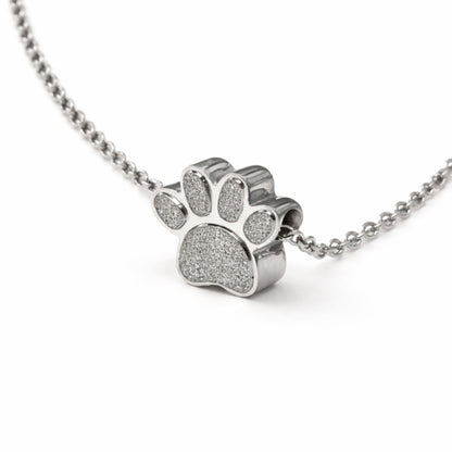 Vue 3/4 du collier empreinte fidèle urne en acier inoxydable argenté mettant en valeur son relief et son compartiment intégré