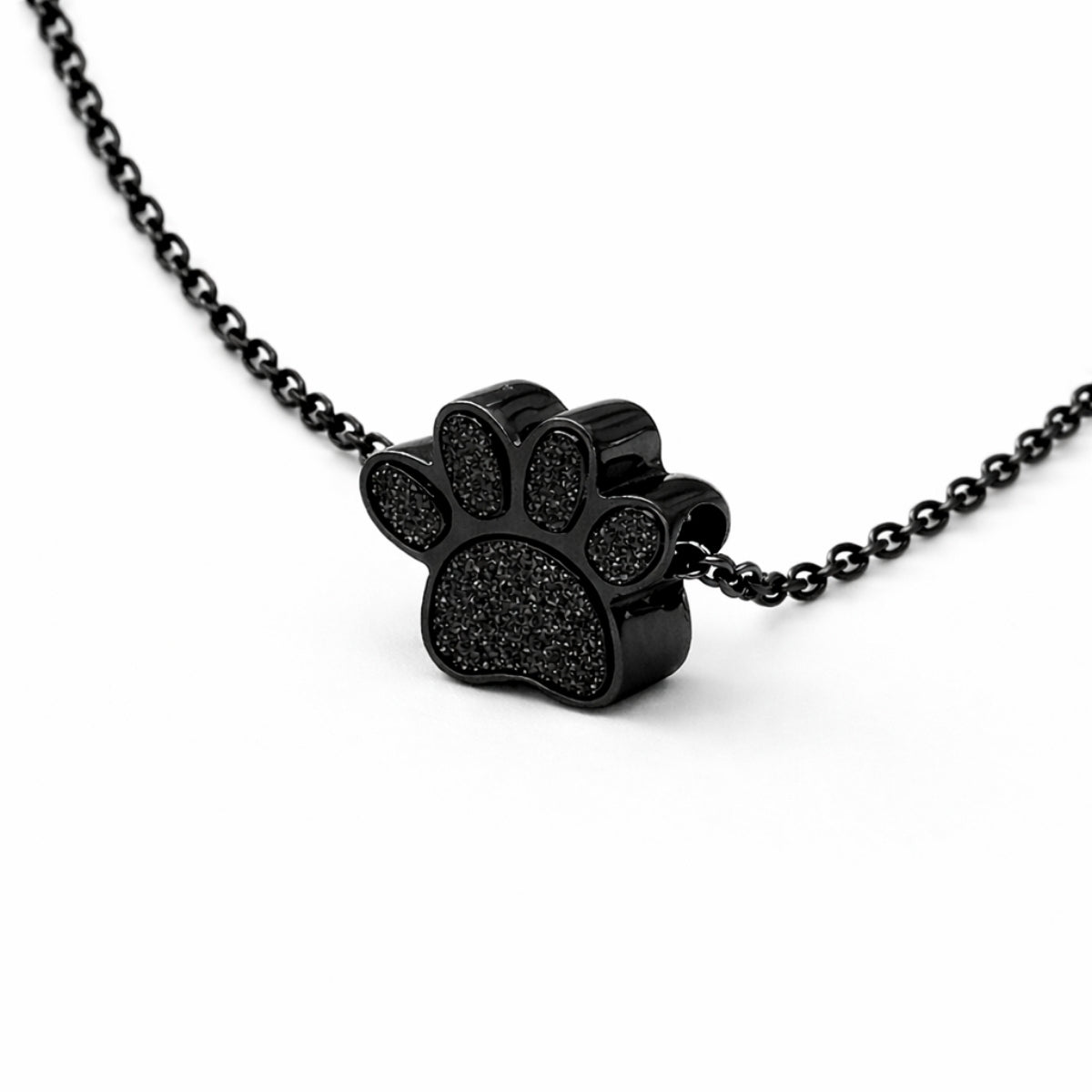 Vue 3/4 du collier empreinte fidèle urne en acier inoxydable noir mettant en valeur son relief et son compartiment intégré