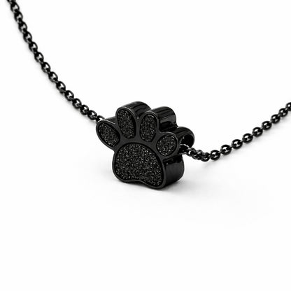 Vue 3/4 du collier empreinte fidèle urne en acier inoxydable noir mettant en valeur son relief et son compartiment intégré