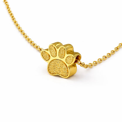 Vue 3/4 du collier empreinte fidèle urne en acier inoxydable doré mettant en valeur son relief et son compartiment intégré