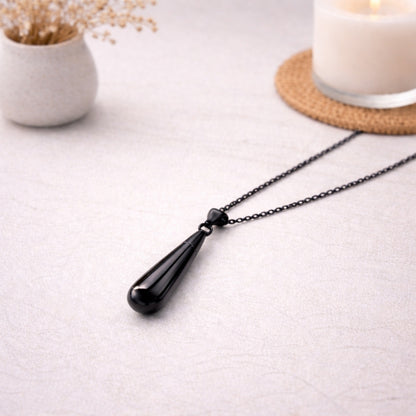 Collier goutte en acier inoxydable noir dans une ambiance élégante et minimaliste
