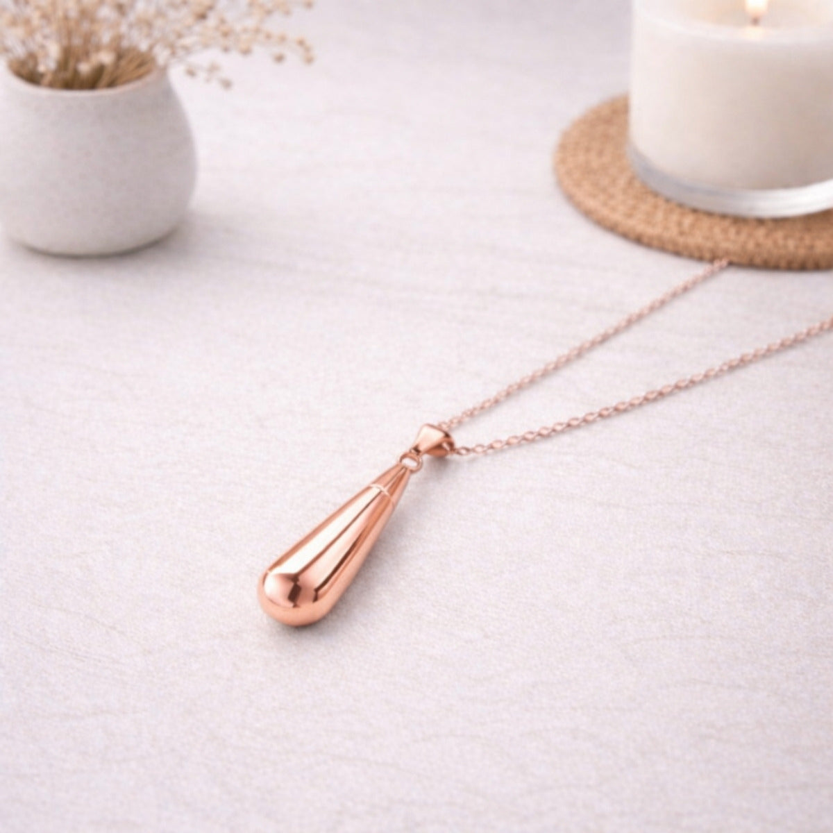 Collier goutte en acier inoxydable rose dans une ambiance élégante et minimaliste