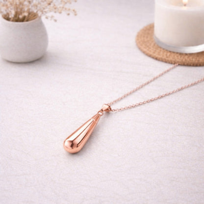 Collier goutte en acier inoxydable rose dans une ambiance élégante et minimaliste