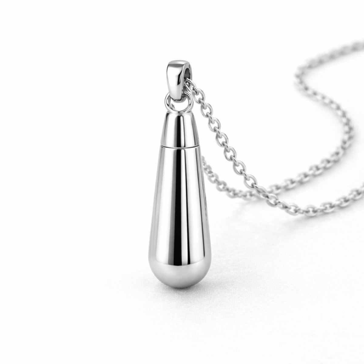 Vue 3/4 du collier goutte urne en acier inoxydable argenté mettant en valeur sa silhouette en goutte et son compartiment intégré