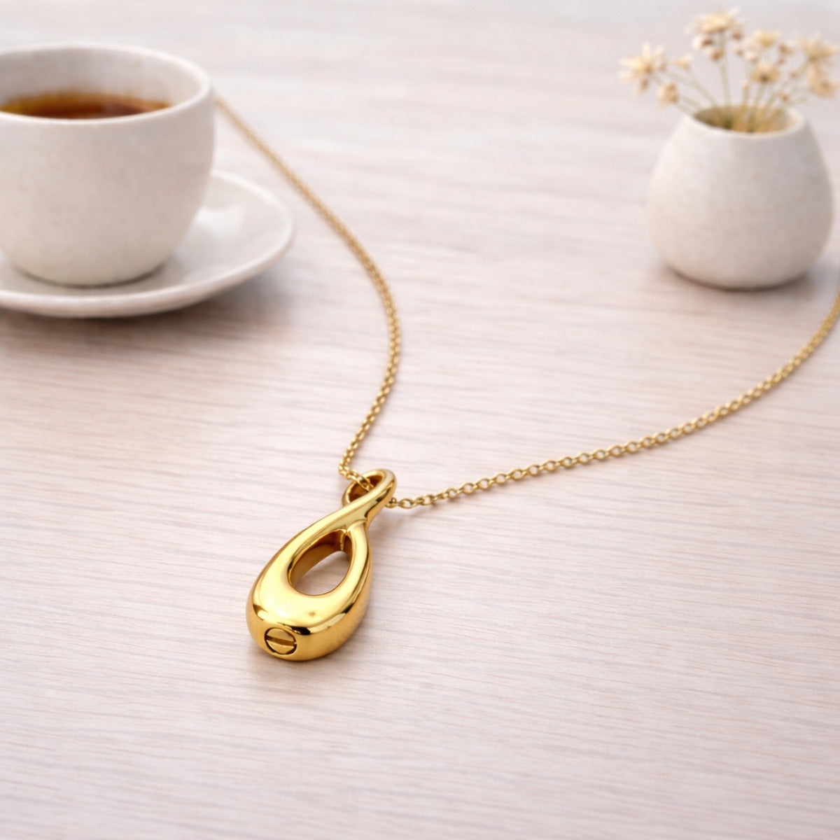Collier Lien Éternel urne doré présenté dans une ambiance claire et élégante