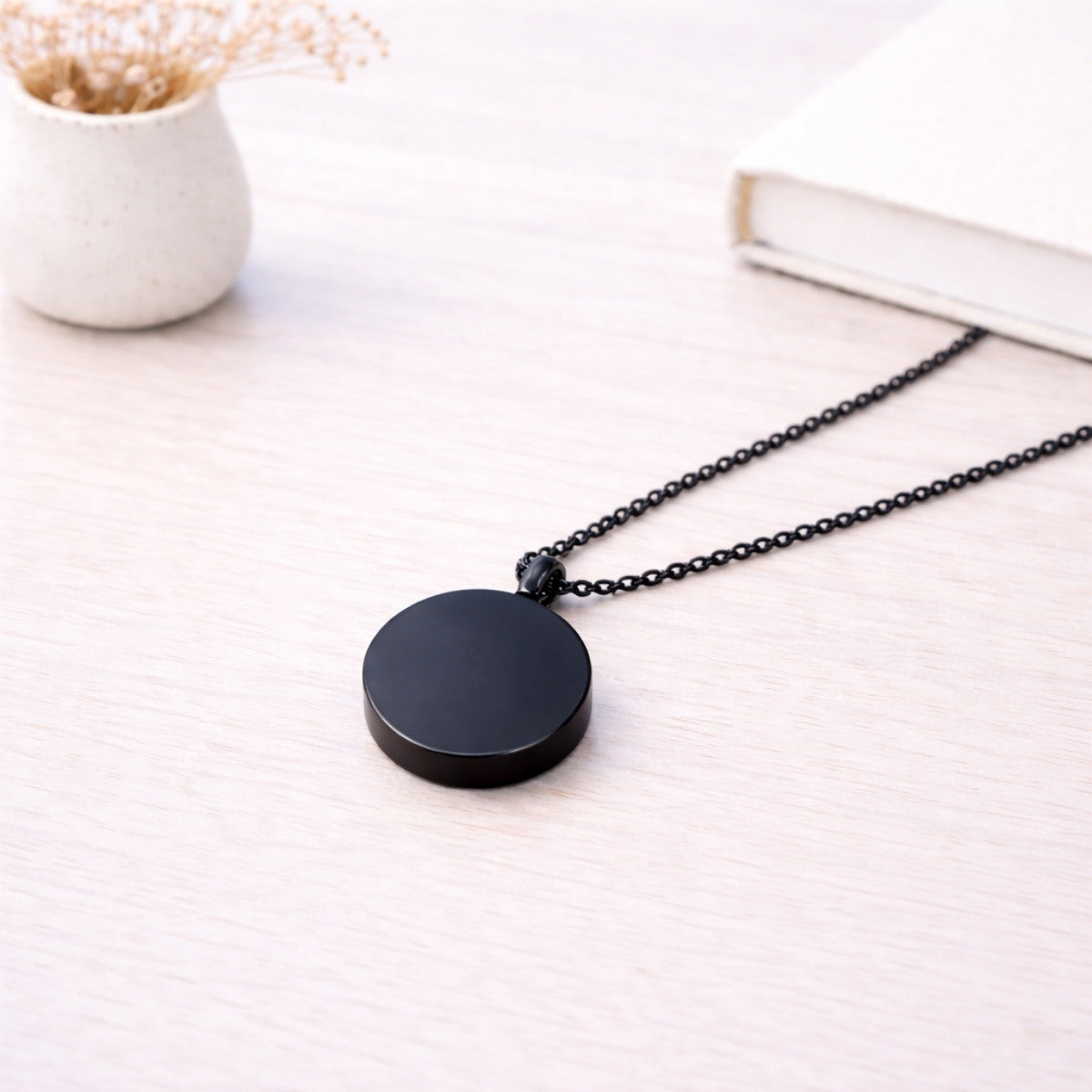 Pendentif cercle éternel en acier inoxydable noir dans une ambiance élégante et minimaliste