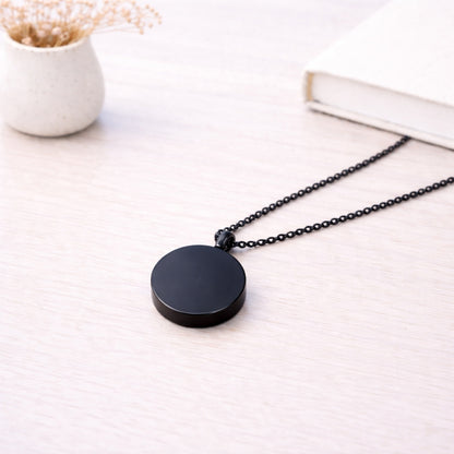 Pendentif cercle éternel en acier inoxydable noir dans une ambiance élégante et minimaliste