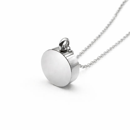 Vue 3/4 du pendentif cercle éternel urne en acier inoxydable argenté mettant en valeur sa silhouette ronde et son compartiment intégré
