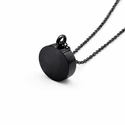 Vue 3/4 du pendentif cercle éternel urne en acier inoxydable noir mettant en valeur sa silhouette ronde et son compartiment intégré