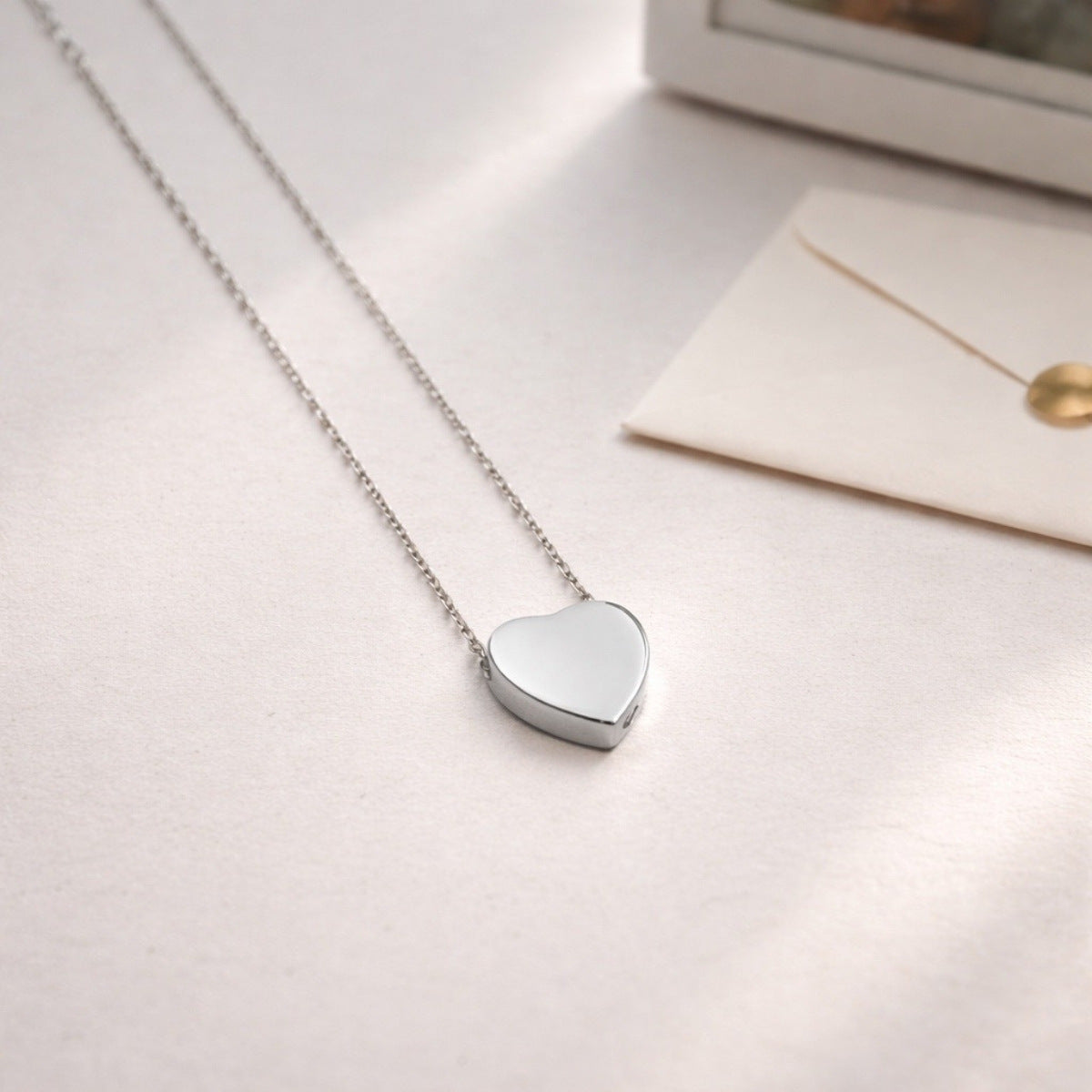 Pendentif cœur souvenir en acier inoxydable argenté dans une ambiance douce et minimaliste