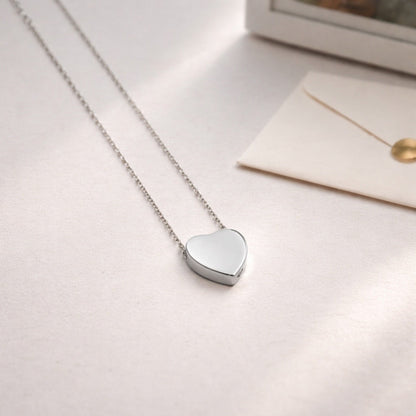 Pendentif cœur souvenir en acier inoxydable argenté dans une ambiance douce et minimaliste
