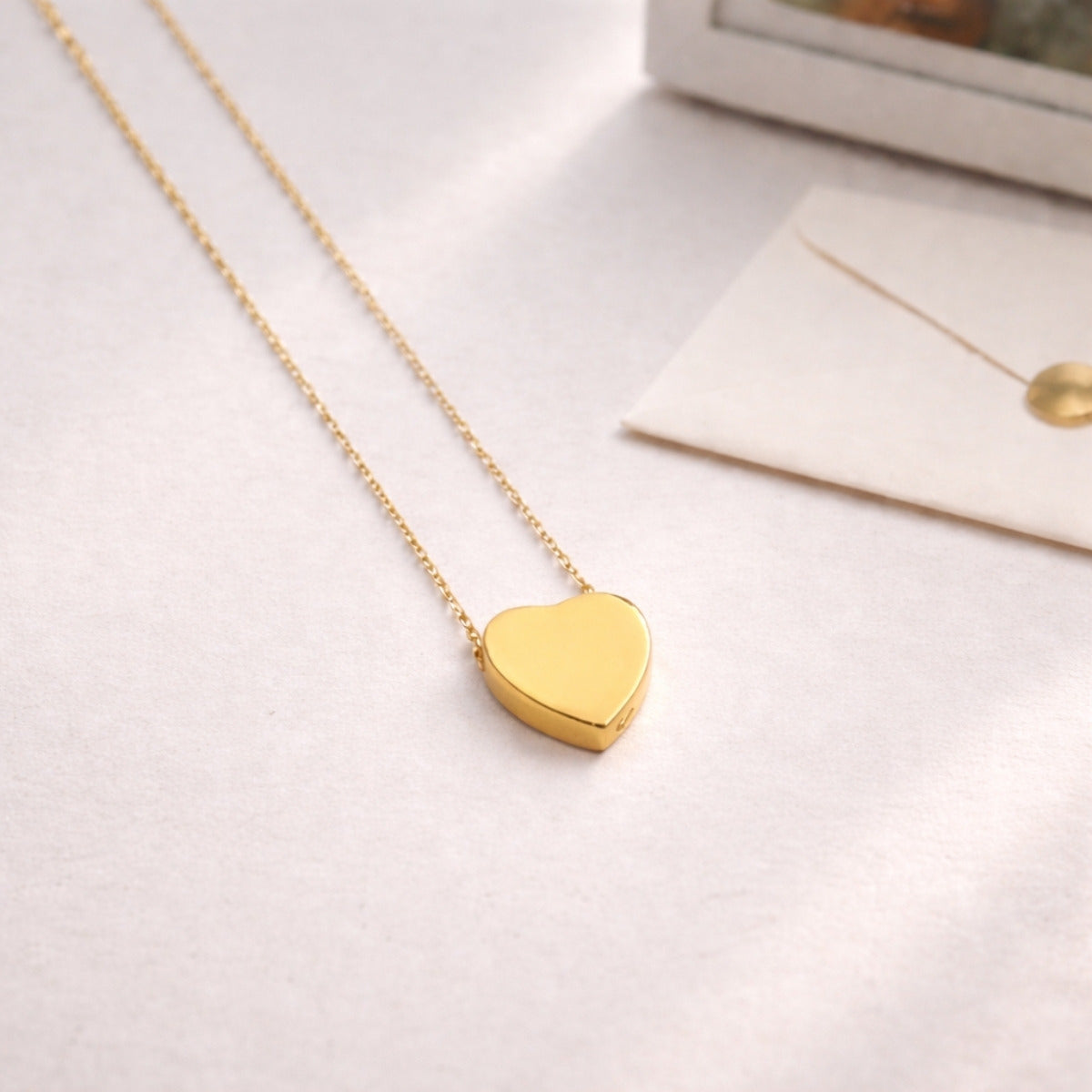 Pendentif cœur souvenir en acier inoxydable doré dans une ambiance douce et minimaliste