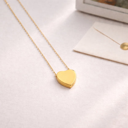 Pendentif cœur souvenir en acier inoxydable doré dans une ambiance douce et minimaliste