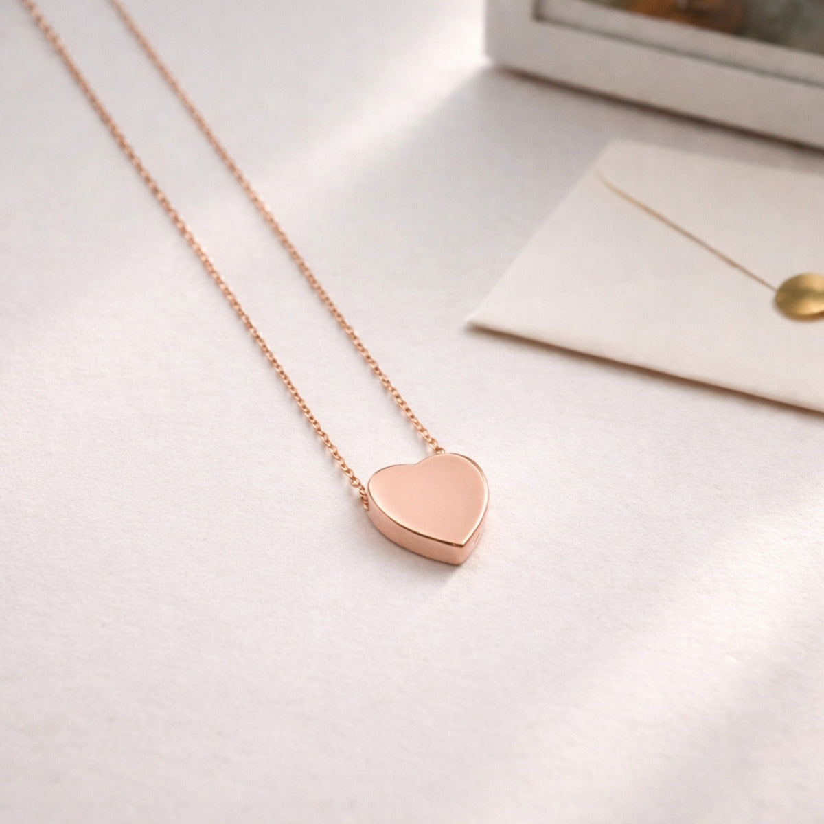 Pendentif cœur souvenir en acier inoxydable rose dans une ambiance douce et minimaliste