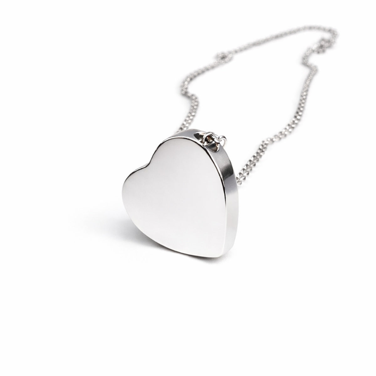 Vue 3/4 du pendentif cœur urne en acier inoxydable argenté mettant en valeur son volume et son compartiment intérieur