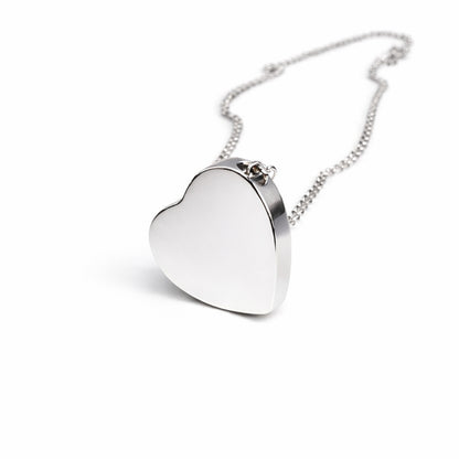 Vue 3/4 du pendentif cœur urne en acier inoxydable argenté mettant en valeur son volume et son compartiment intérieur