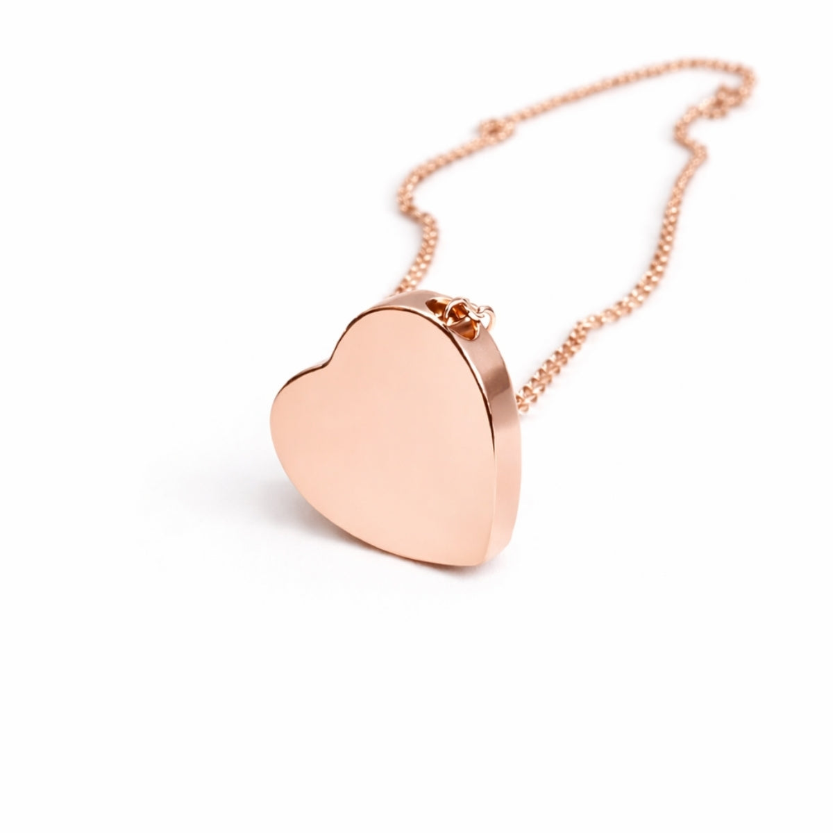 Vue 3/4 du pendentif cœur urne en acier inoxydable rose mettant en valeur son volume et son compartiment intérieur