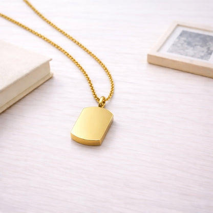Pendentif Héritage urne doré présenté dans une ambiance claire et élégante