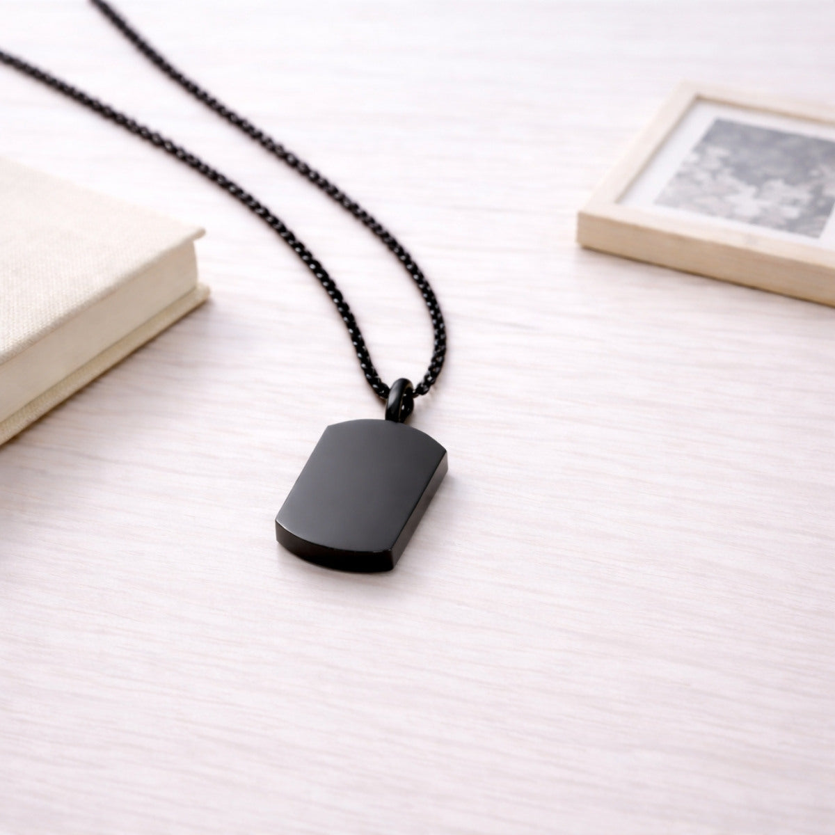 Pendentif Héritage urne noir présenté dans une ambiance claire et élégante