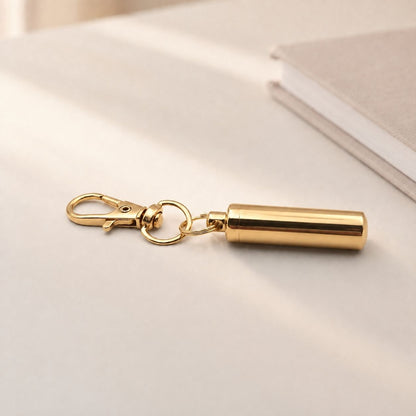 Porte-clés Capsule du Souvenir en acier inoxydable doré dans une ambiance élégante et minimaliste