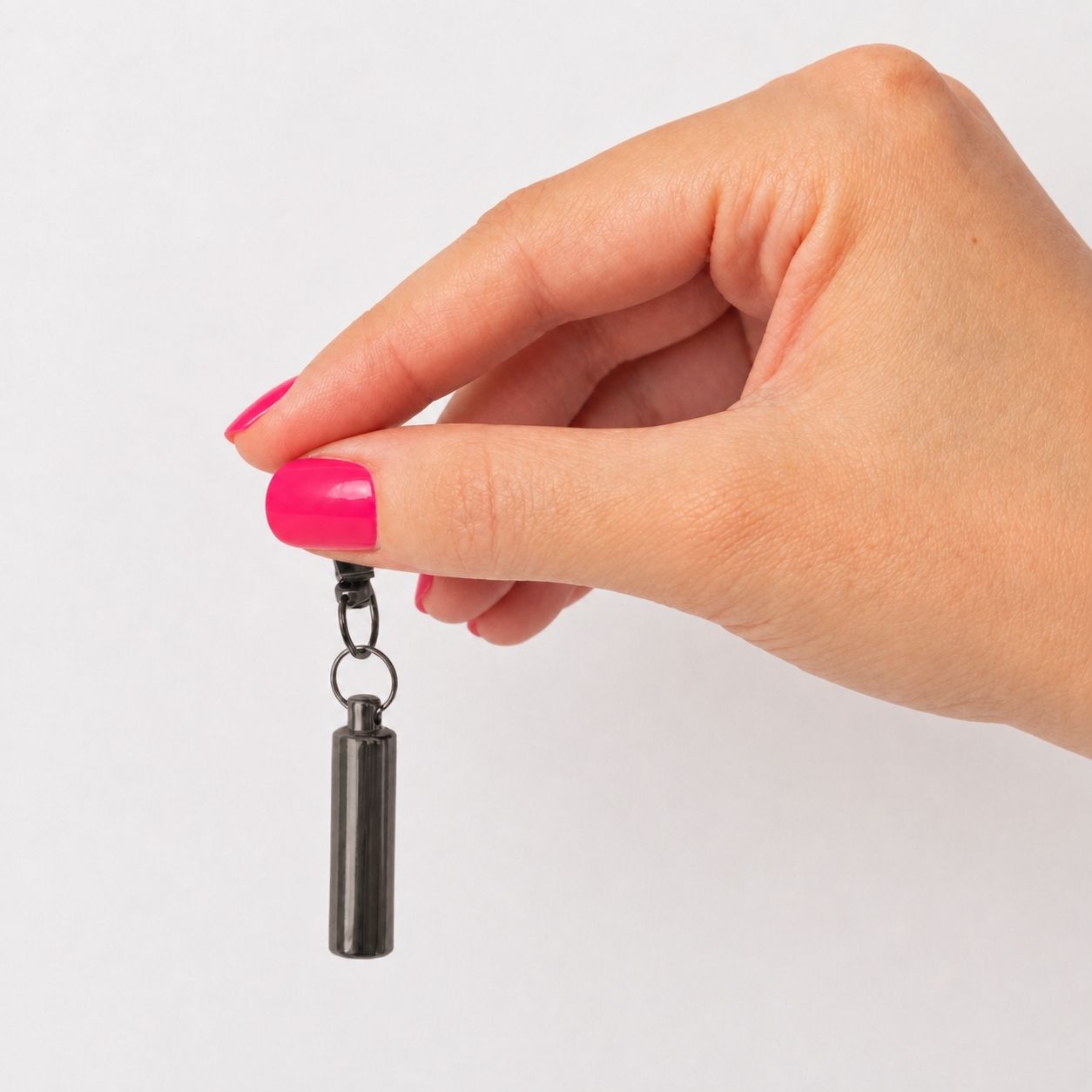 Porte-clés Capsule du Souvenir noir tenu en main avec urne cylindrique discrète – Mementery