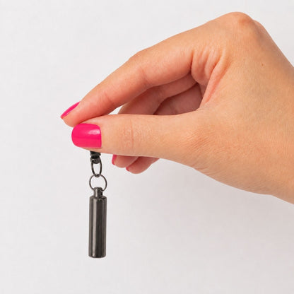 Porte-clés Capsule du Souvenir noir tenu en main avec urne cylindrique discrète – Mementery
