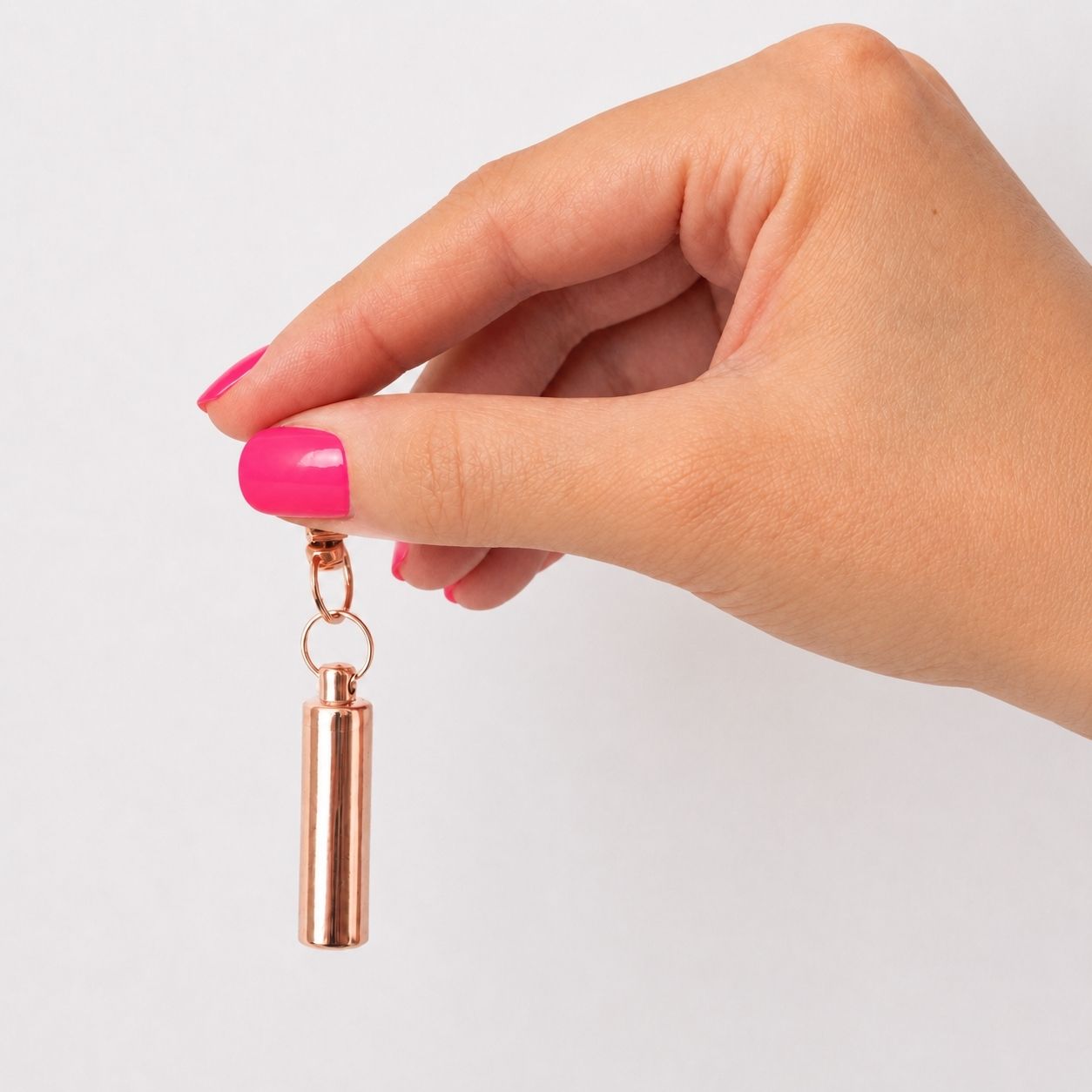Porte-clés Capsule du Souvenir rose tenu en main avec urne cylindrique discrète – Mementery
