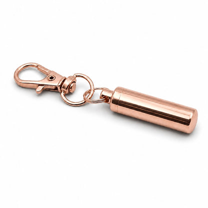 Vue 3/4 du porte-clés Capsule du Souvenir urne en acier inoxydable rose avec mousqueton et capsule cylindrique