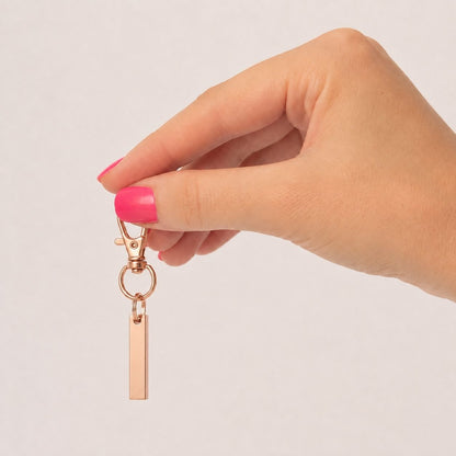 Porte-clés Écrin du Souvenir rose tenu en main avec urne rectangulaire discrète – Mementery