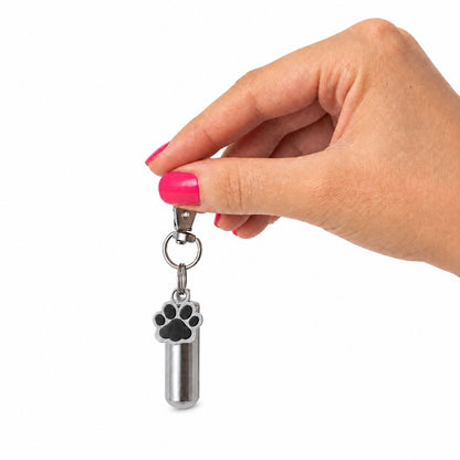 Porte-clés Empreinte du Souvenir argenté tenu en main avec urne cylindrique et pendentif patte – Mementery