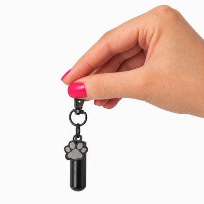 Porte-clés Empreinte du Souvenir noir tenu en main avec urne cylindrique et pendentif patte – Mementery