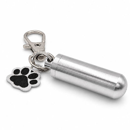 Vue 3/4 du porte-clés Empreinte du Souvenir urne en acier inoxydable argenté avec pendentif patte et cylindre souvenir