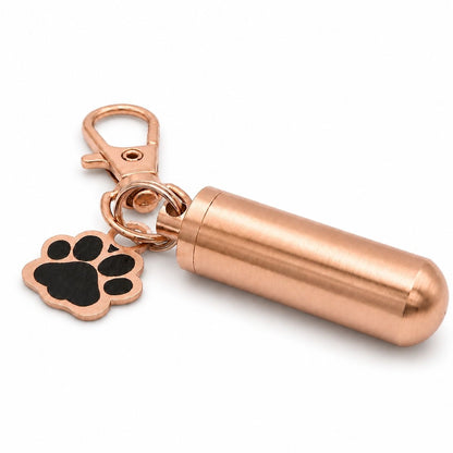 Vue 3/4 du porte-clés Empreinte du Souvenir urne en acier inoxydable rose avec pendentif patte et cylindre souvenir